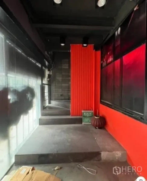 零售空间 出租在Khlong Toei, Bangkok - 长形入口走廊，红墙、磨砂面板与天花射灯。