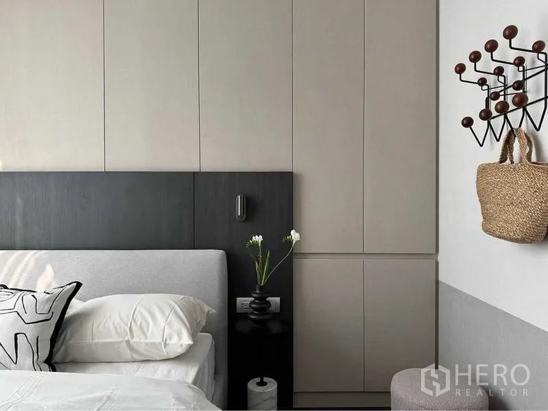 Condominium for rent or sale in Watthana, Bangkok - Close-up of bed with black headboard, built-in wardrobes and side table with vase.