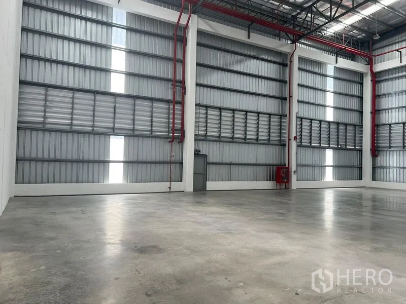 Factory for rent in Bang Pakong, Chachoengsao - Spacious warehouse bay with steel cladding walls, skylight panels and red fire safety piping.
