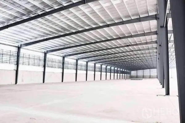 Warehouse for rent in Mueang Samut Sakhon, Samut Sakhon - Expansive warehouse interior with high steel roof, wide-spaced columns, ventilation panels and smooth concrete floor.