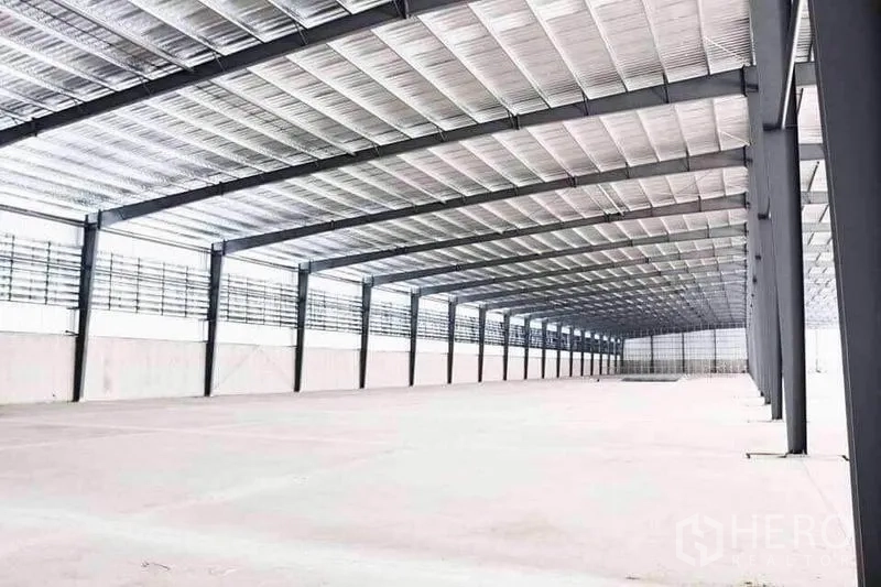 Warehouse for rent in Mueang Samut Sakhon, Samut Sakhon - Expansive warehouse interior with high steel roof, wide-spaced columns, ventilation panels and smooth concrete floor.