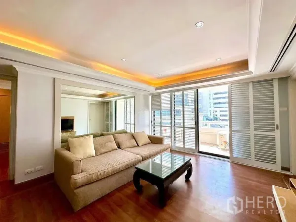 Condominium for rent - Bright living room with beige sofa, wood floors and sliding doors to a balcony with city views.