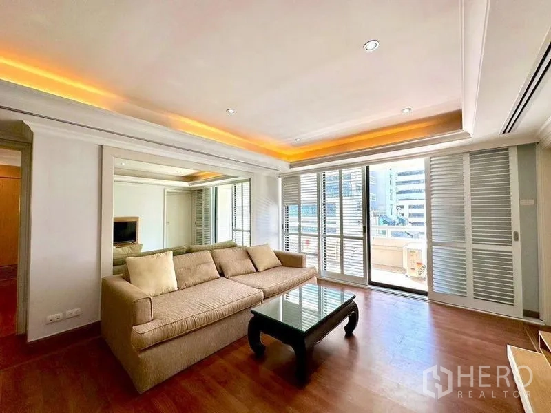Condominium for rent - Bright living room with beige sofa, wood floors and sliding doors to a balcony with city views.