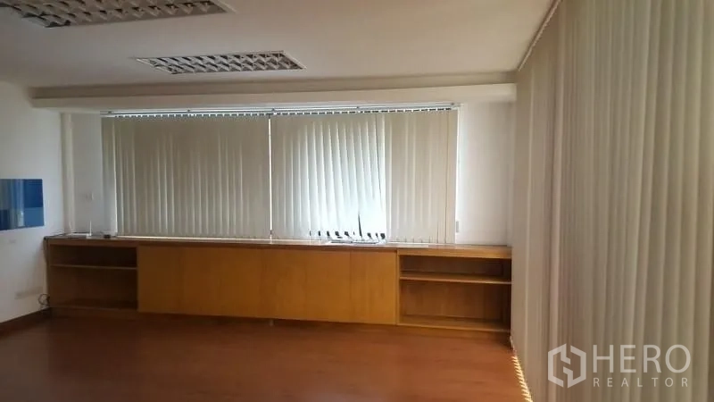 Warehouse for rent in Suan Luang, Bangkok - Large office space with built-in cabinets below windows and vertical blinds.