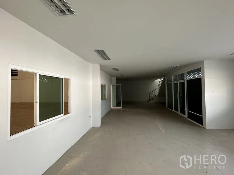 Factory for rent in Bang Bo, Samut Prakan - Ground-floor office space with tiled floors, internal windows to the warehouse and glass partitions.
