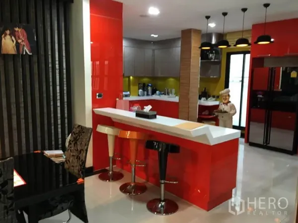 Detached House for rent in Khlong Toei, Bangkok - Modern kitchen with red cabinetry, breakfast bar and bar stools under pendant lights.