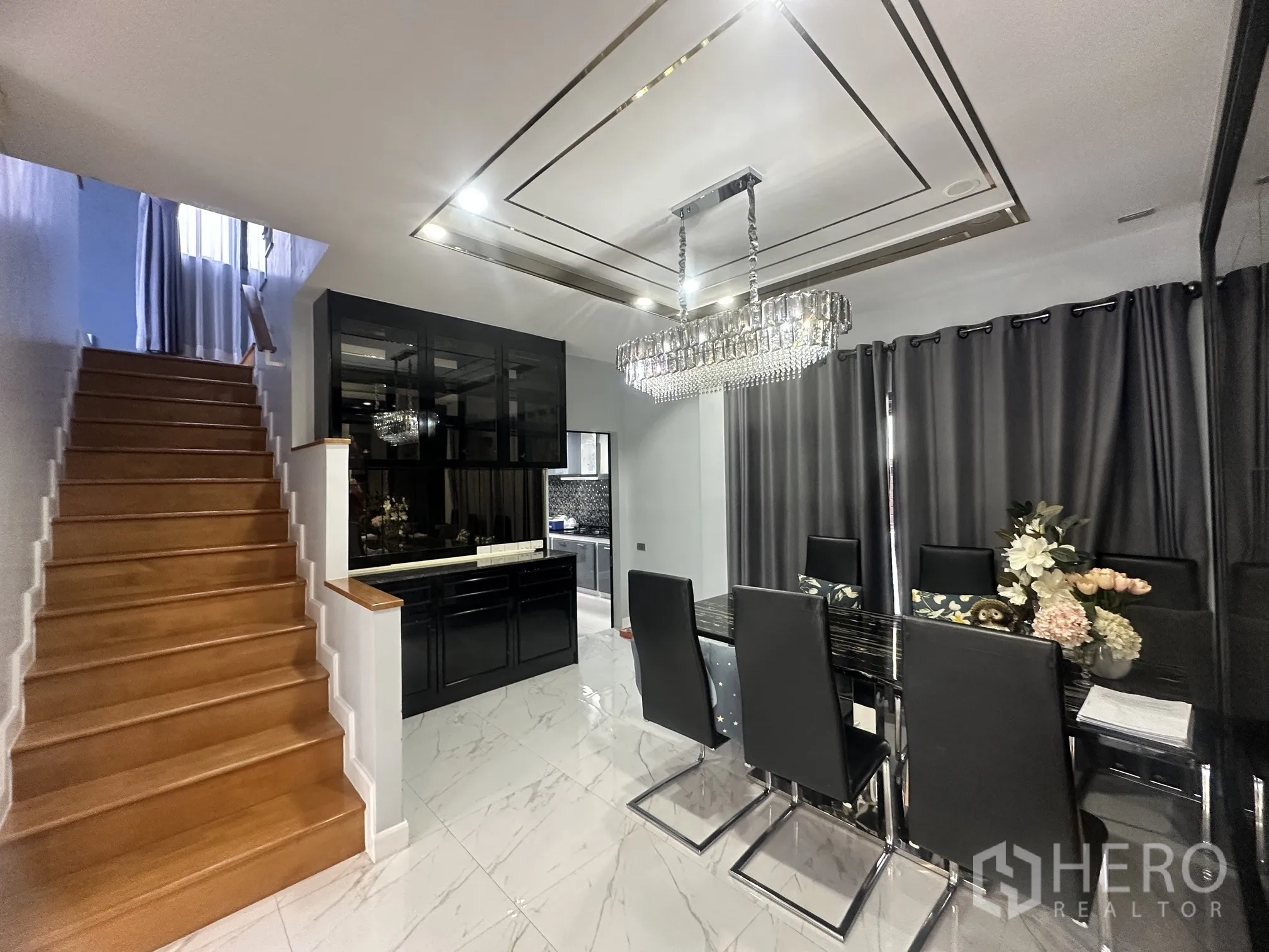 Detached House for sale in Pak Kret, Nonthaburi - Dining area with crystal chandelier beside a wooden staircase and built-in cabinet.