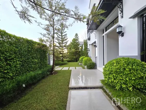 Detached House for rent in Saphan Sung, Bangkok - Side yard with trimmed hedge, terrace and walkway leading to the lawn.