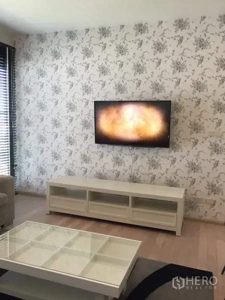 公寓 出租在Watthana, Bangkok - 客厅设壁挂电视、白色电视柜与花纹特色墙面，简洁时尚。