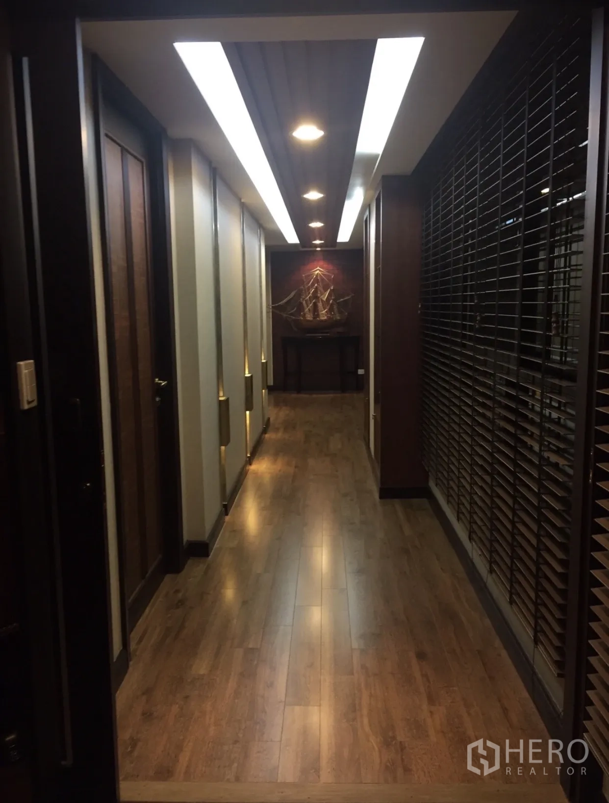 Condominium for sale in Yan Nawa, Bangkok - Contemporary corridor with wooden flooring and linear recessed ceiling lights.