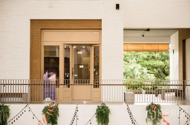 零售空间 出租在Khlong Toei, Bangkok - 沿开放式走廊的店铺入口外观，点缀绿植。