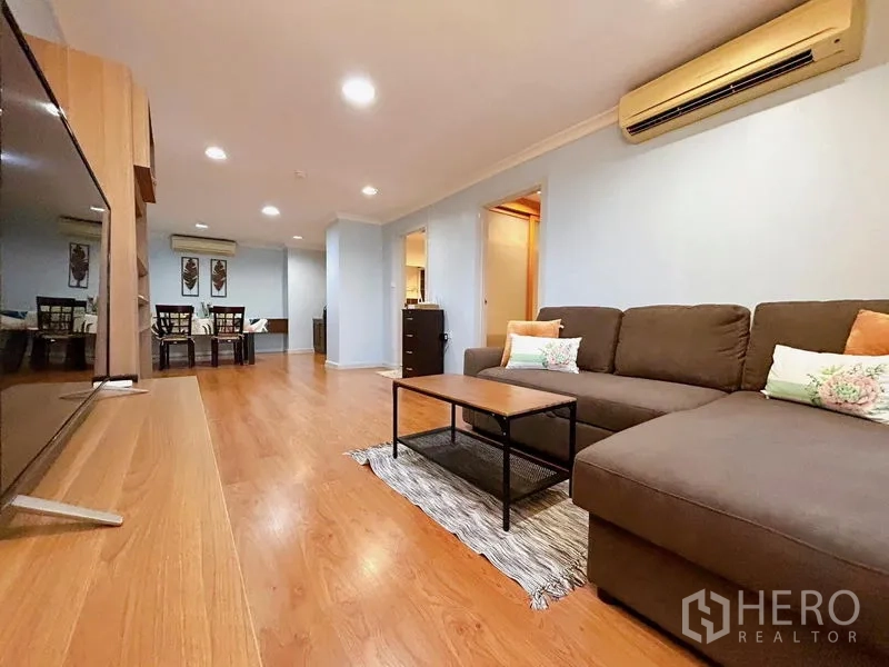 公寓 出租在Watthana, Bangkok - 舒适客厅，L型沙发、茶几与空调。