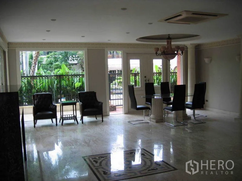 บ้าน ให้เช่าในWatthana, Bangkok - ห้องรับประทานอาหารมีโคมระย้าและประตูกระจกเปิดสู่ชานสวนที่เขียวขจี