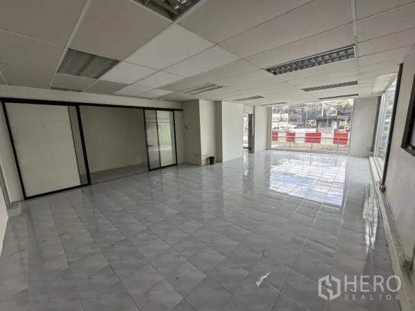 Warehouse for rent in Suan Luang, Bangkok - Bright tiled showroom space with floor-to-ceiling windows at the front.