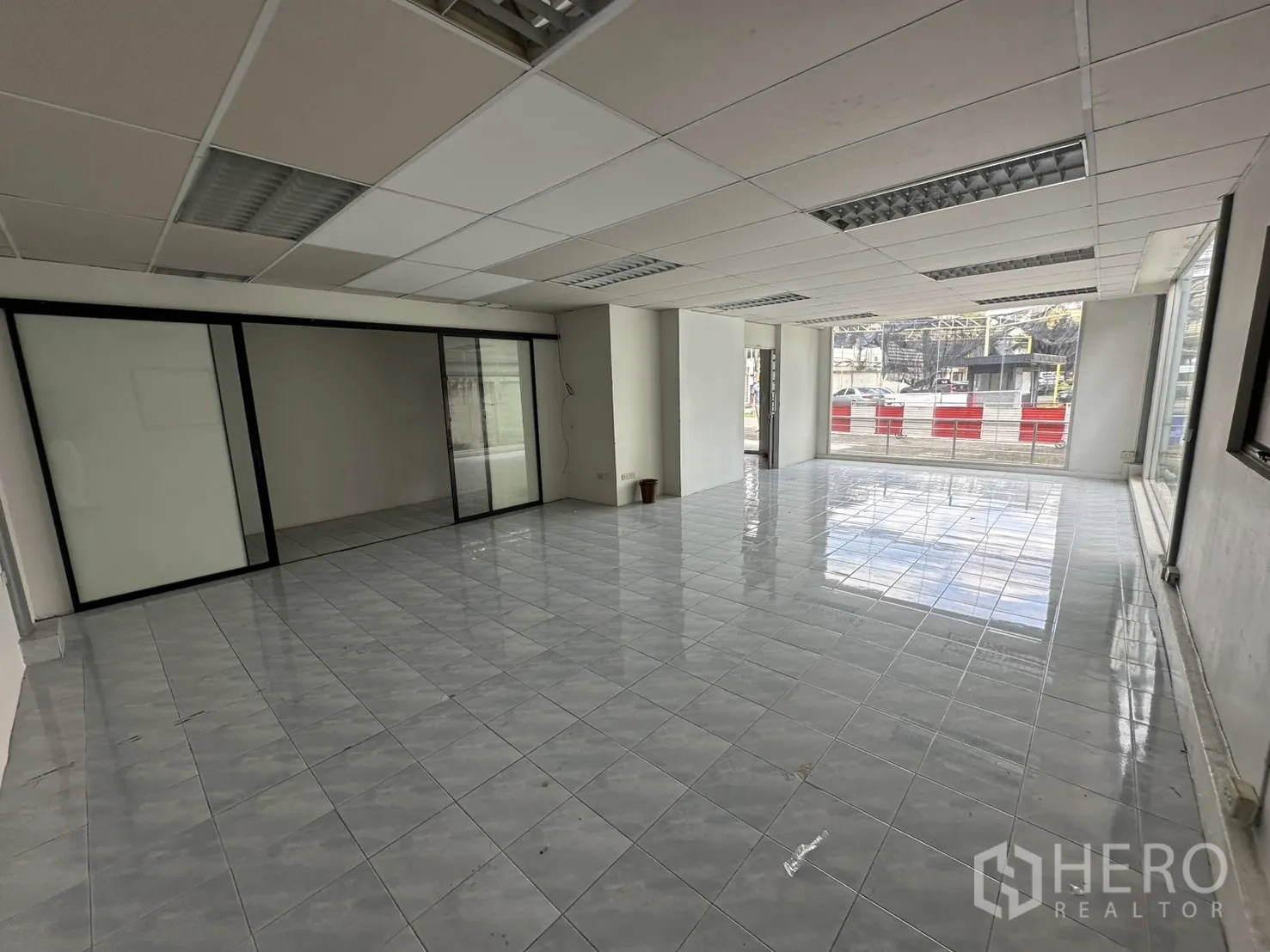 Warehouse for rent in Suan Luang, Bangkok - Bright tiled showroom space with floor-to-ceiling windows at the front.