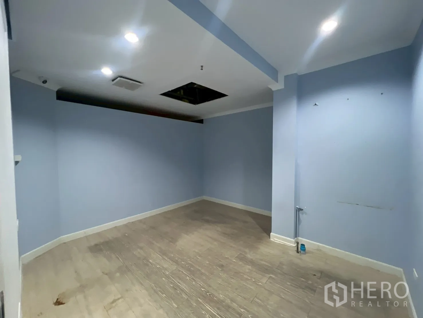 Office Space for rent in Watthana, Bangkok - Light blue room with recessed lights, pale wood floor and service point on the wall.