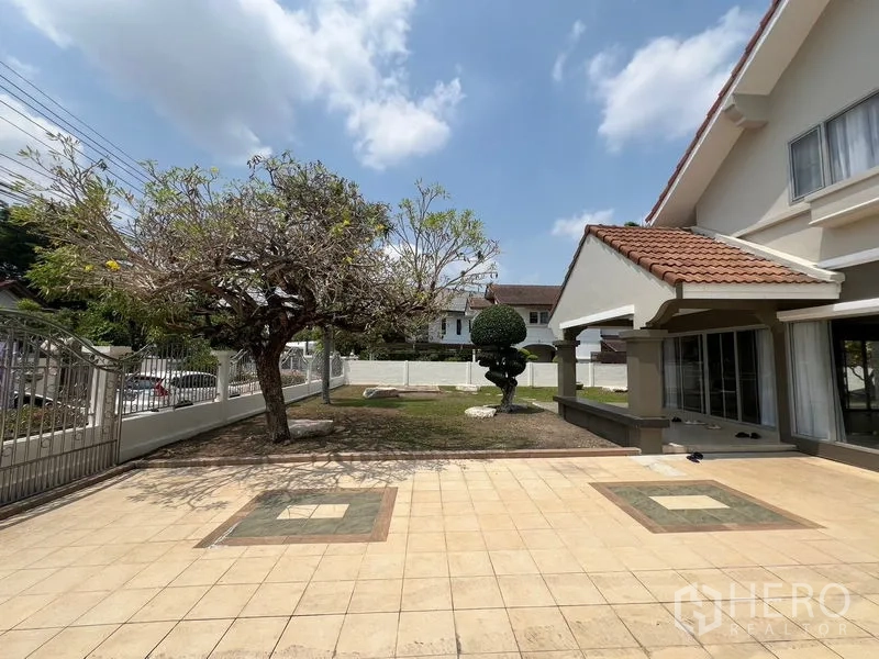 Detached House for sale in Mueang Pathum Thani, Pathum Thani - Front yard of a detached house with tiled patio, mature tree and covered porch.