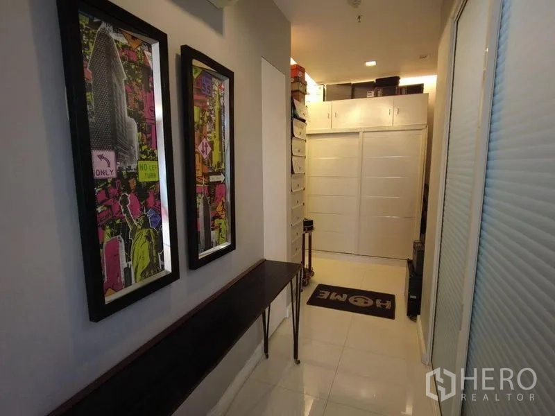 Condominium for rent in Watthana, Bangkok - Hallway with framed art, slim console table and built-in cabinet.