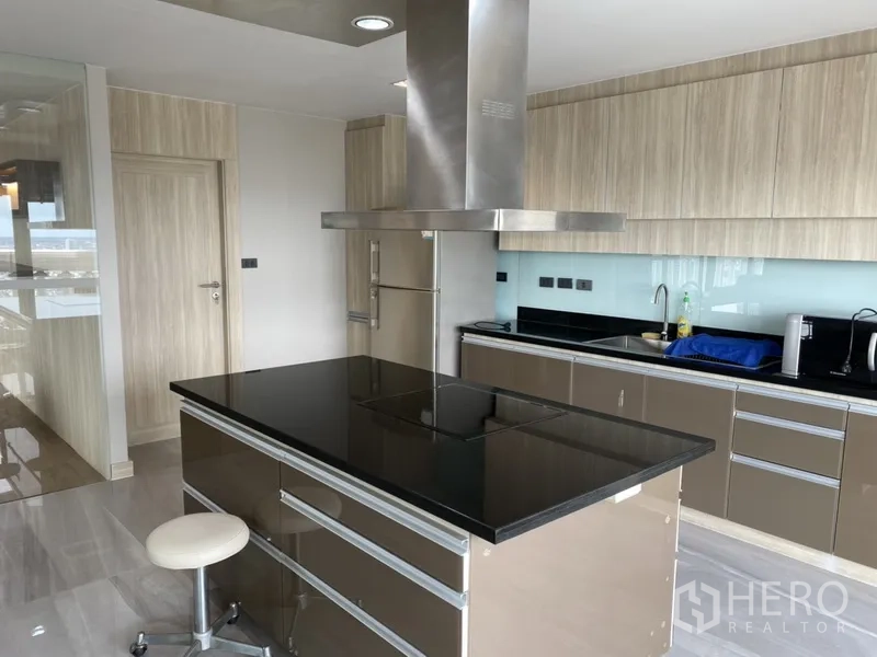 公寓 出租在Bang Rak, Bangkok - 现代厨房配黑色石材中岛、不锈钢烟机、充足橱柜与家电。