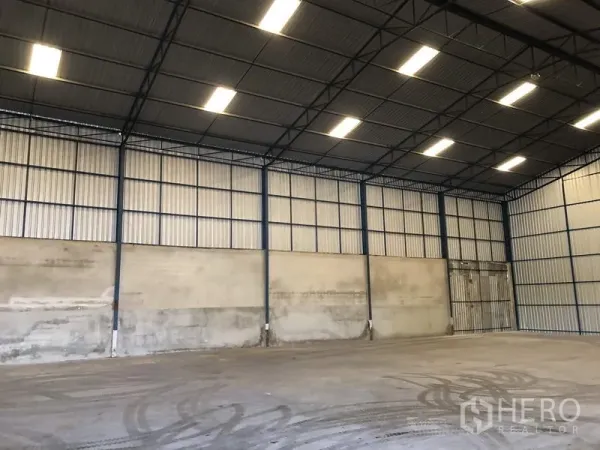 货栈 出租在Pathum Thani - 大跨距仓库，金属夹芯墙体，宽幅推拉门与均匀顶灯照明。