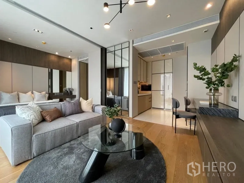 Condominium for sale - Modern lounge with sectional sofa, round rug, built-in cabinetry and kitchenette view.