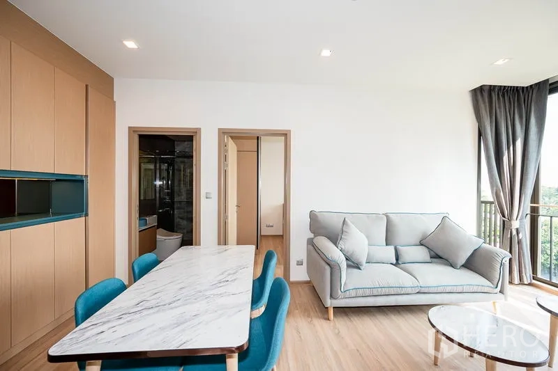 คอนโด ให้เช่าในWatthana, Bangkok - มุมนั่งเล่นพร้อมโซฟาและโต๊ะทานอาหาร ข้างหน้าต่างสูงจรดเพดานที่มุมห้อง