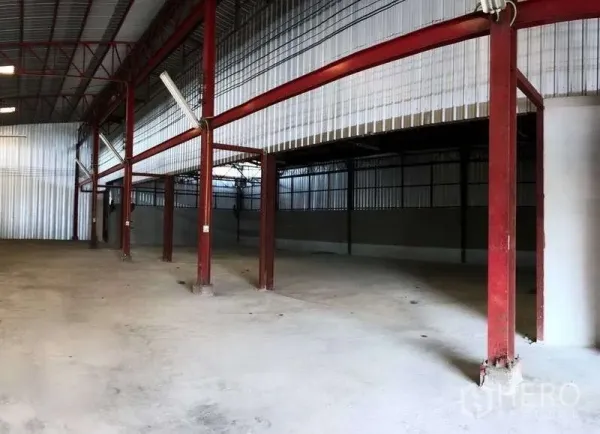 Warehouse for rent in Phra Pradaeng, Samut Prakan - Open warehouse bay with red steel columns, partial mezzanine-like area and wide concrete floor.