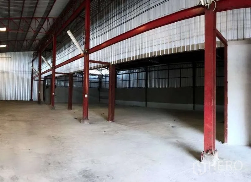 Warehouse for rent in Phra Pradaeng, Samut Prakan - Open warehouse bay with red steel columns, partial mezzanine-like area and wide concrete floor.