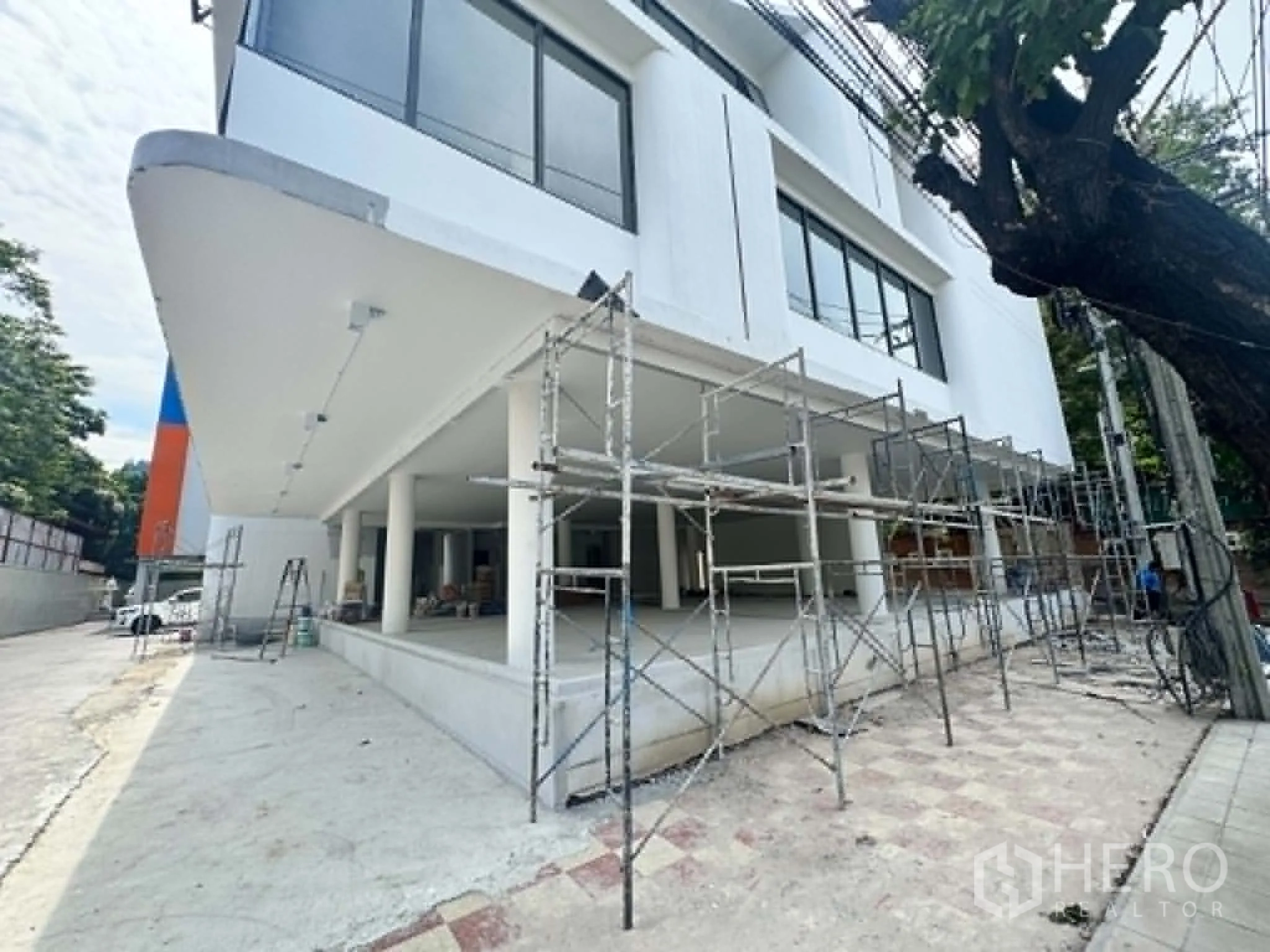 Retail Space for rent in Watthana, Bangkok - Modern white commercial building exterior with scaffolding and an open ground floor.