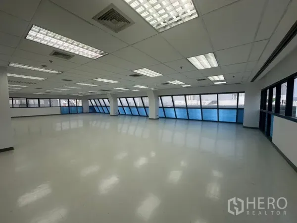 办公空间 出租在Phaya Thai, Bangkok - 转角办公区，环绕的蓝色带状窗、白色立柱与浅色地面。