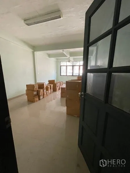 Shophouse for sale in Sathon, Bangkok - Bright upper-floor room with large windows, tiled floor and stacked storage boxes.