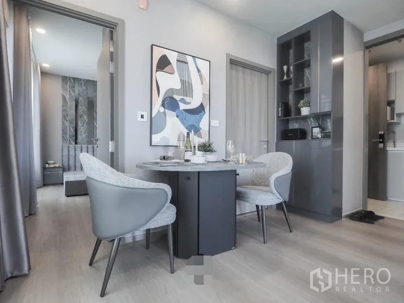 Condominium for rent in Samut Prakan - Compact dining area for two with built-in shelving and wall art.