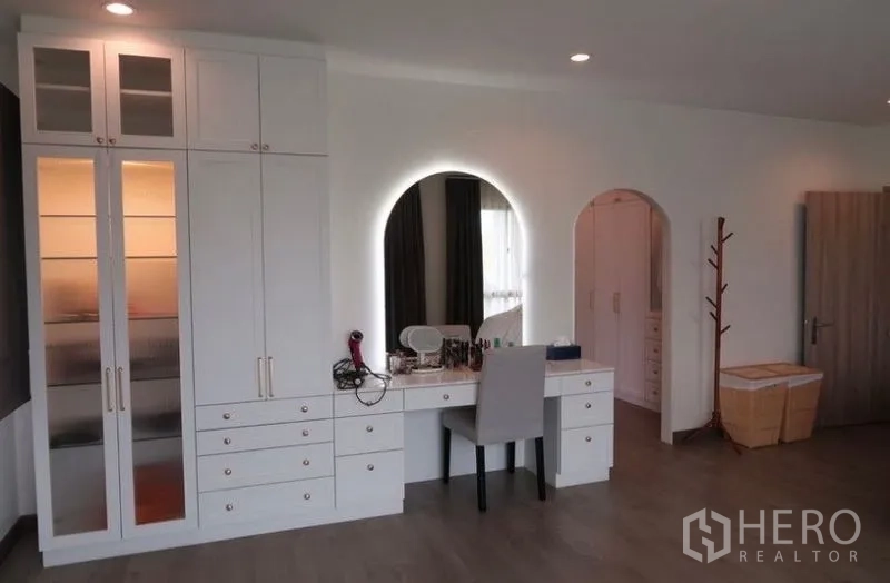 Detached House for rent or sale in Saphan Sung, Bangkok - Dressing area with built-in vanity, backlit round mirror, and storage cabinets.