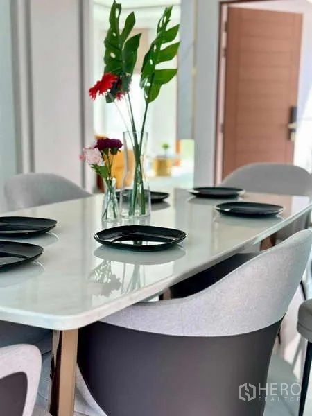 Detached House for rent or sale in Bang Phli, Samut Prakan - Dining area with marble-top table, grey chairs and vases of fresh flowers.