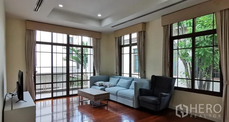 บ้าน ให้เช่าในWatthana, Bangkok - ห้องพักผ่อนพร้อมโซฟามุม ทีวี และหน้าต่างเต็มบานมองเห็นสวน