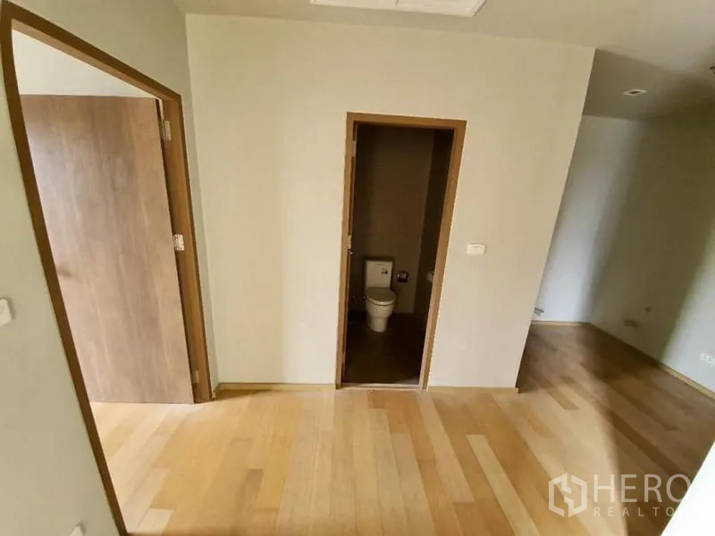 Condominium for sale in Ratchathewi, Bangkok - Hallway view into a tiled bathroom and adjacent room with light wood floors.