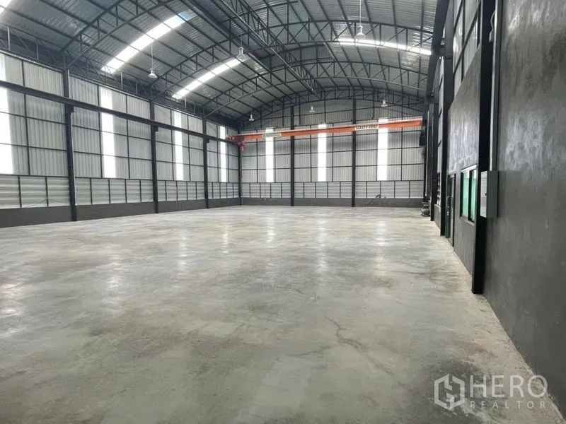 Warehouse for rent in Ban Bueng, Chon Buri - Large high-clearance warehouse interior with steel trusses, skylights, and polished concrete floor.