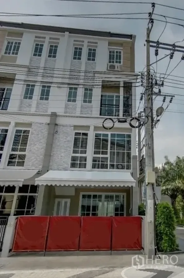 สำนักงานที่บ้าน ให้เช่าในBang Na, Bangkok - อาคารโฮมออฟฟิศมุมตึกสไตล์โมเดิร์น หน้าต่างกระจกบานใหญ่ กันสาดสีขาว และรั้วสีแดงริมถนนเงียบสงบ