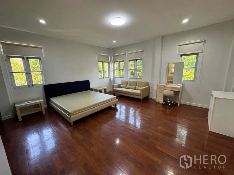 Detached House for rent in Prawet, Bangkok - Bright corner bedroom with multiple windows and polished wooden flooring.