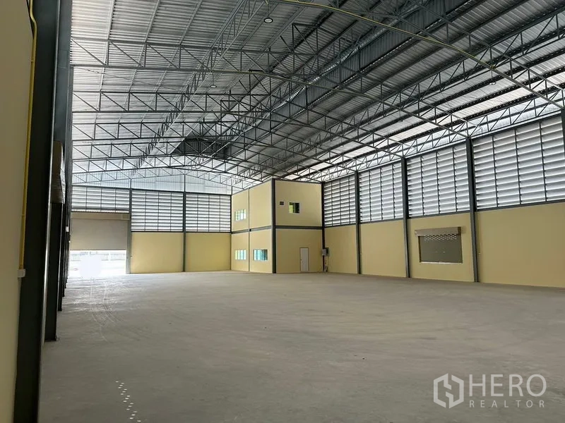 Warehouse for rent or sale in Bang Phli, Samut Prakan - High-clearance warehouse bay with mezzanine office cube, skylights and smooth concrete slab.