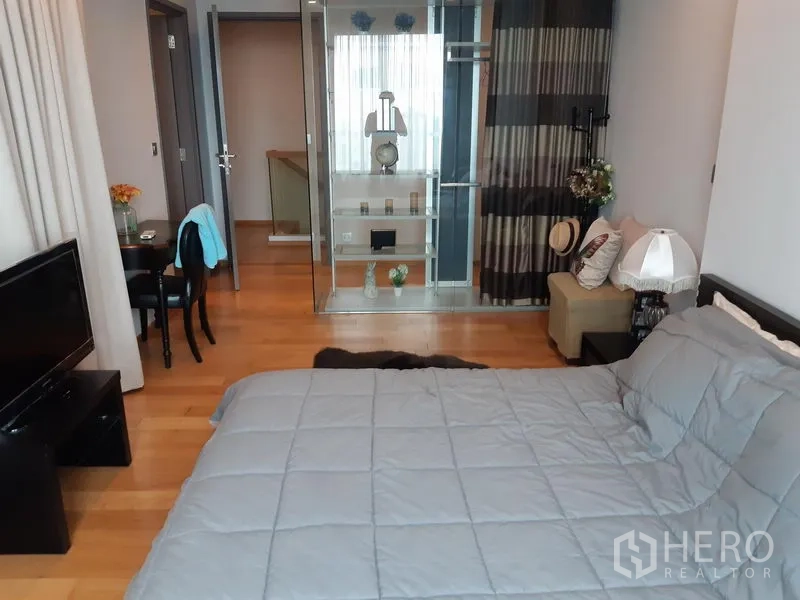 Condominium for rent in Khlong Toei, Bangkok - Master bedroom view showing a glass partition, seating corner, and small dining area.