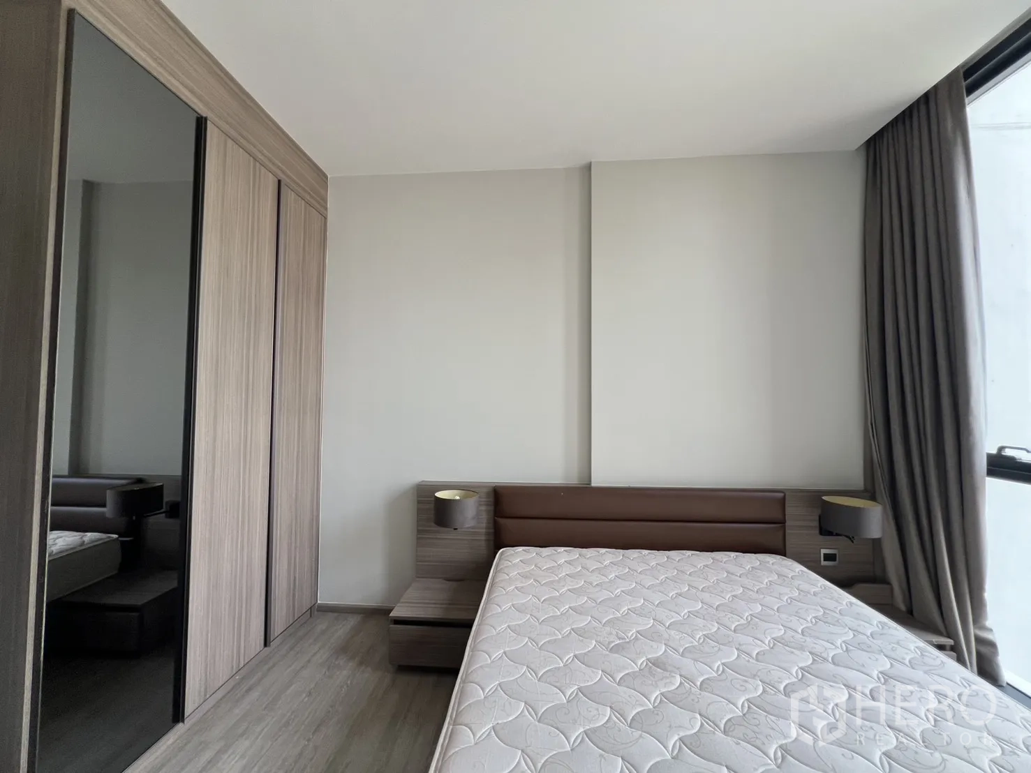 Condominium for rent in Watthana, Bangkok - Bedroom showing a built-in wardrobe with mirrored panel next to the bed.