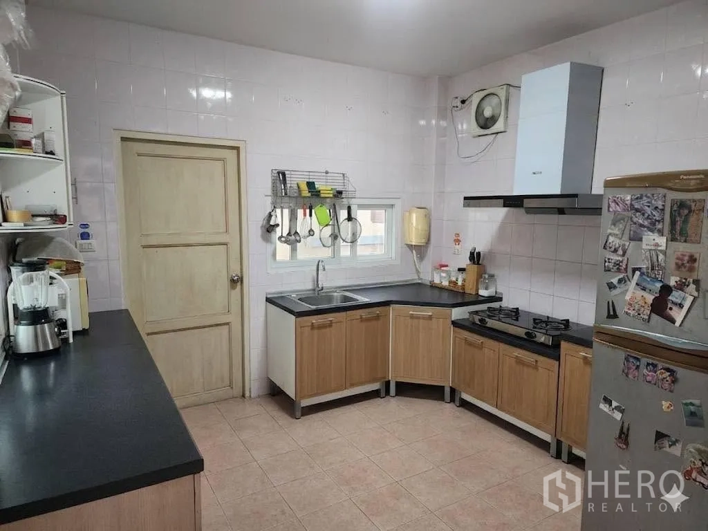 Detached House for rent in Lam Luk Ka, Pathum Thani - Fully tiled kitchen with L-shaped counters, gas hob, range hood, and window.