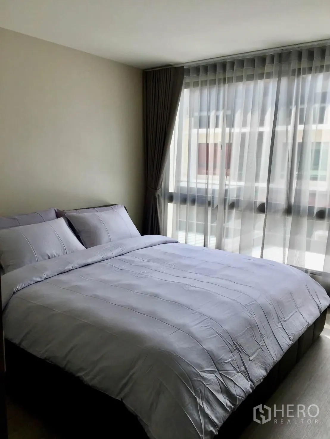 Townhouse for rent in Lat Phrao, Bangkok - Bedroom with large bed, curtains and floor-to-ceiling window.