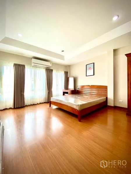 ทาวน์เฮาส์ ให้เช่าในPrawet, Bangkok - ห้องนอนใหญ่ เพดานหลุม หน้าต่างกว้าง ผ้าม่าน แอร์ และเตียงไม้.