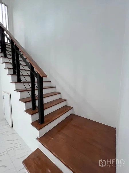 Home Office for sale in Lat Krabang, Bangkok - Corner stair landing with wood treads, black railing and storage under stairs.