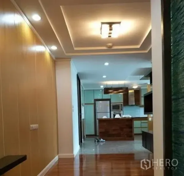 Condominium for rent or sale in Watthana, Bangkok - Hallway to an open kitchen featuring ceiling lights, wood floors, an island and modern cabinets.