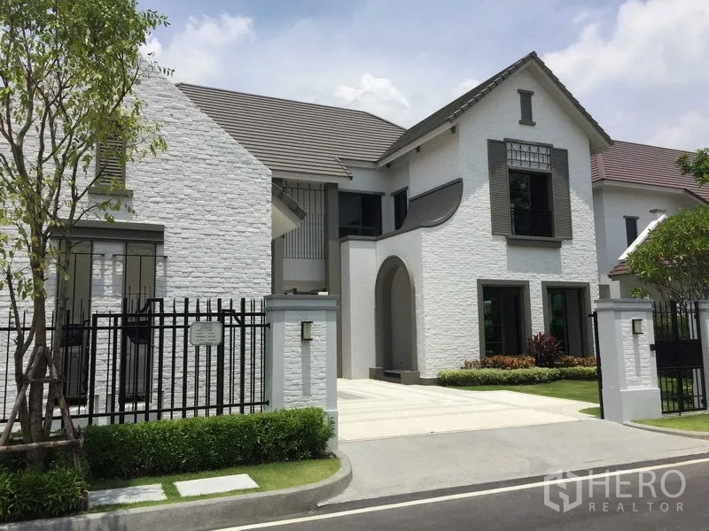 Detached House for sale in Mueang Samut Prakan, Samut Prakan - Modern white-brick detached house with gated driveway and landscaped front garden.