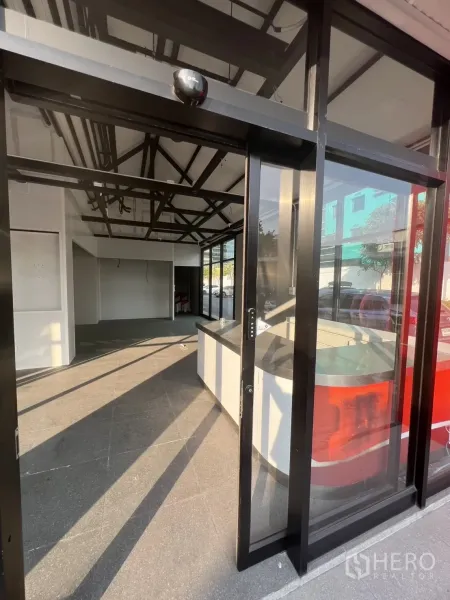 พื้นที่ขายปลีก ให้เช่า - ประตูกระจกบานเลื่อน เปิดสู่พื้นที่ร้านสว่างพร้อมเคาน์เตอร์ด้านหน้า.
