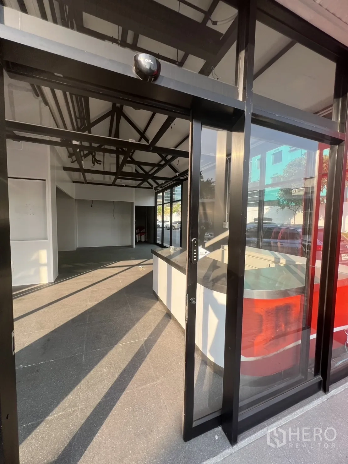 พื้นที่ขายปลีก ให้เช่า - ประตูกระจกบานเลื่อน เปิดสู่พื้นที่ร้านสว่างพร้อมเคาน์เตอร์ด้านหน้า.